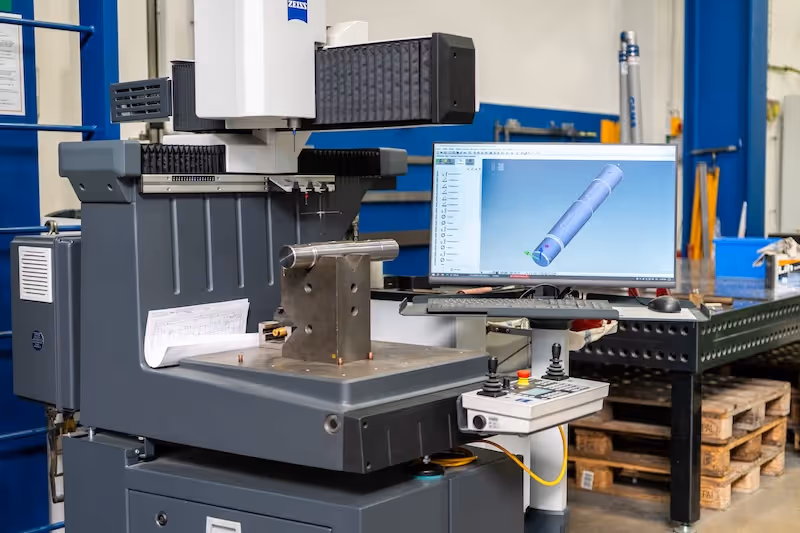 Souřadnicový měřicí stroj Zeiss s upnutým dílem a 3D modelem na monitoru